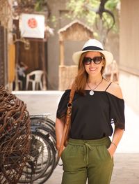 Portrait of smiling young woman wearing sunglasses standing outdoors