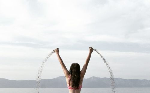 Woman with arms raised against sky