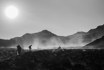 Silhouette people on mountain against sky