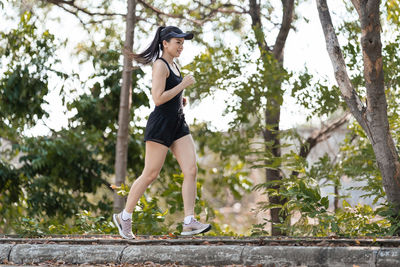 Side view of young woman against trees