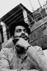 Portrait of young man standing against built structure