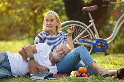 Man sleeping on woman leg sitting on grass