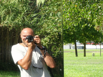 Reflection of man photographing through camera on glass