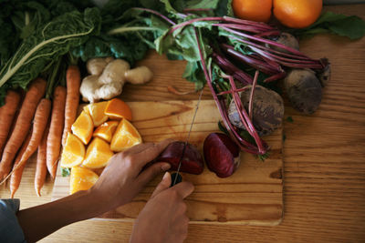 Cropped hand of man holding vegetables on table