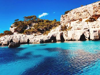 Scenic view of rocks in sea against blue sky