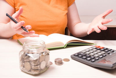 Midsection of woman reading book on table