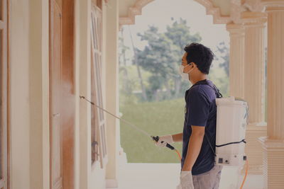 Side view of young man looking through window