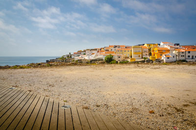 Beach by buildings against sky