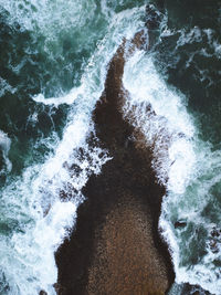 High angle view of waves splashing on rocks