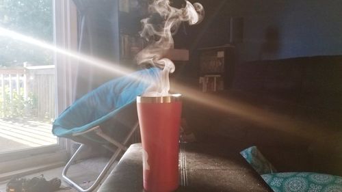 Close-up of smoke emitting from glass on table