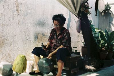 Woman sitting on seat against wall