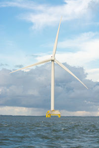 Windmills on sea against sky