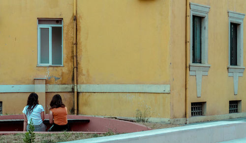 Rear view of people sitting outside building