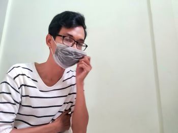 Portrait of young woman standing against wall