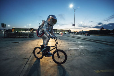 Spaceman in the city at night on parking lot riding bmx bike