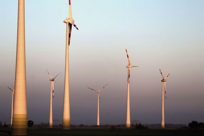 Low angle view of wind turbine against sky during sunset