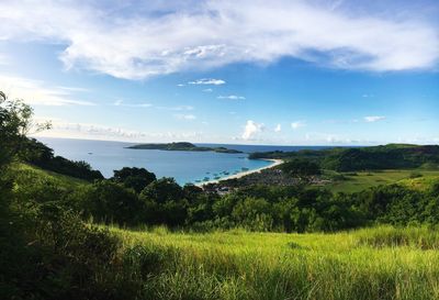 Scenic view of sea by field against sky