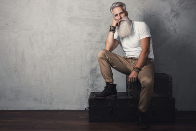 Young man sitting against wall