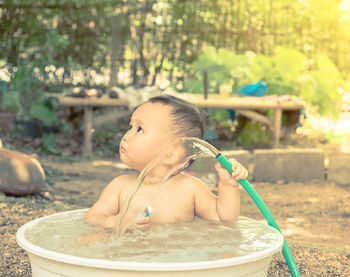 Cute boy holding hose while sitting in tube