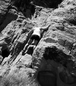 Low angle rear view of woman climbing on rocky mountain