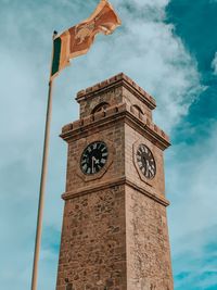 Low angle view of flag by clock tower against sky