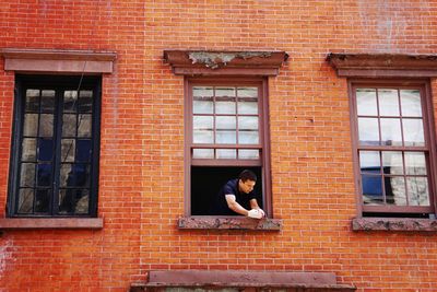 Woman sitting on brick wall of building