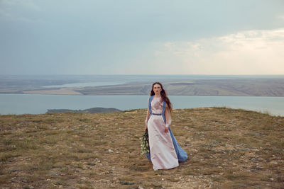 Portrait of young woman standing against sea