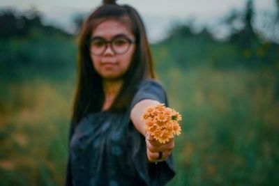 Portrait of beautiful young woman standing on field