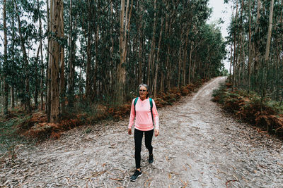 Smiling woman walking by trees in forest