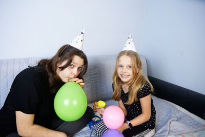 Portrait of happy friends with balloons against sky