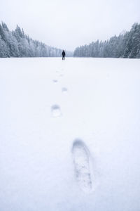 Footprints of man standing on snow covered field