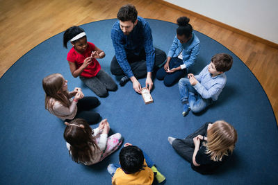 High angle view of teacher playing with children on floor at school