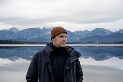 Portrait of young man standing in lake during winter