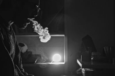 Close-up of man smoking in illuminated room