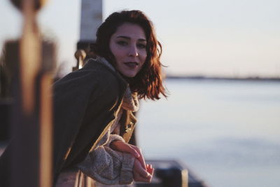 Portrait of beautiful young woman standing against sky