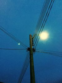 Low angle view of electricity pylon against blue sky