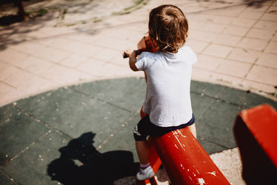 Child playing in the park on a wooden horse.