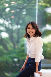 Portrait of smiling young woman sitting outdoors