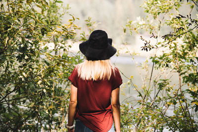 Rear view of woman standing by plants and lake