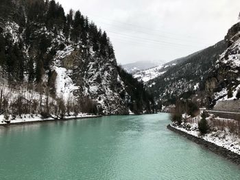 Scenic view of river by tree mountains against sky