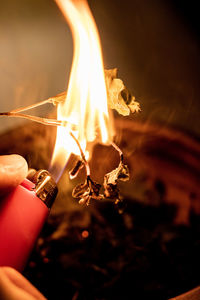Close-up of hands holding burning candle