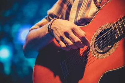 Midsection of man playing guitar