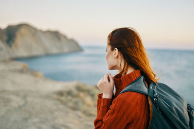 Young woman at beach against sky