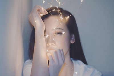 Close-up of young woman with illuminated string light