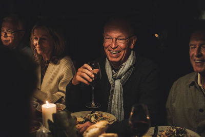 Happy senior man with friends during dinner party at night