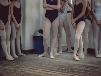 Low section of ballet dancers standing on wooden floor
