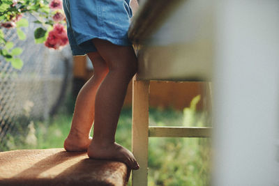 Low section of boy standing on chair by table in yard