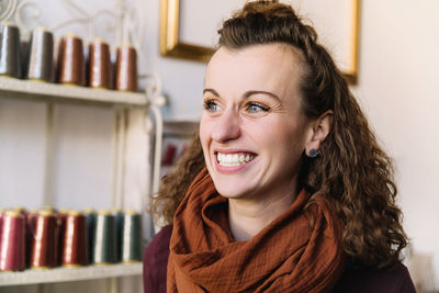 A woman with expressive blue eyes and curly hair laughs, store concept