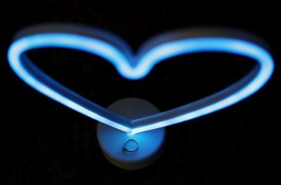 Close-up of heart shape light painting against black background