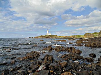 Lighthouse by sea against sky